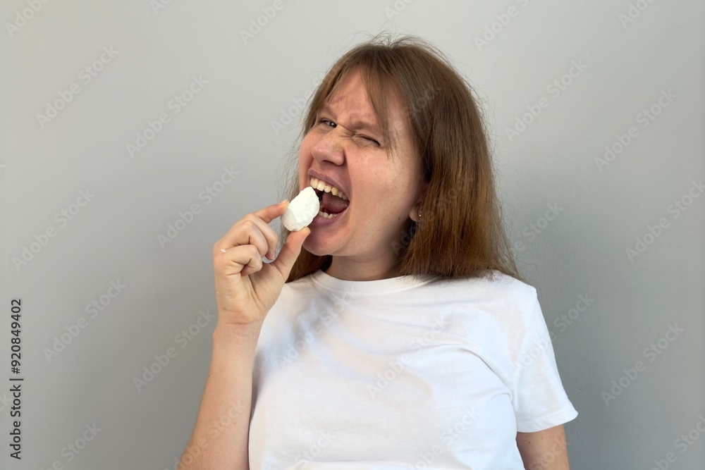beautiful woman holding piece of chalk, biting. concept eat chalk, health, calcium beautiful woman holding piece of chalk, biting. concept eat chalk, health, calcium