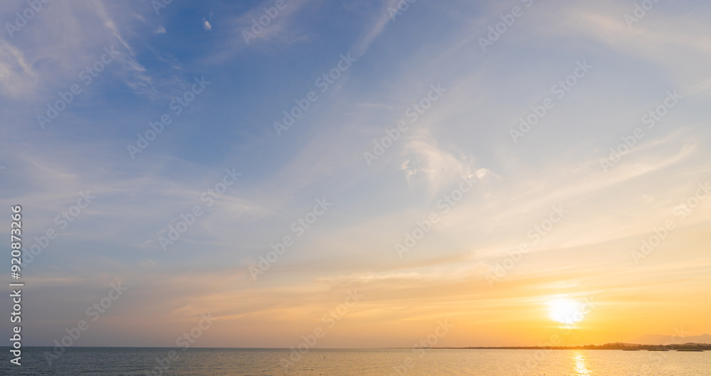 Sunset sky clouds over sea in the evening with orange, yellow sunlight on golden hour, horizon sea sky landscape nature background Sunset sky clouds over sea in the evening with orange, yellow sunlight on golden hour, horizon sea sky landscape nature background