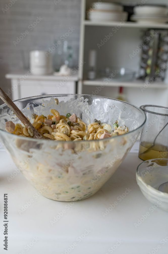 Traditional german pasta salad fresh prepared in the kitchen with mayonnaise, pickles, sausage, green peas and eggs in a bowl Traditional german pasta salad fresh prepared in the kitchen with mayonnaise, pickles, sausage, green peas and eggs in a bowl