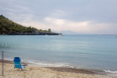 View of the promontory with the ancient lookout tower from the beach in the bay.  Cloudy bay of Marina di Camerota at twilight, Salerno, Italy. photo