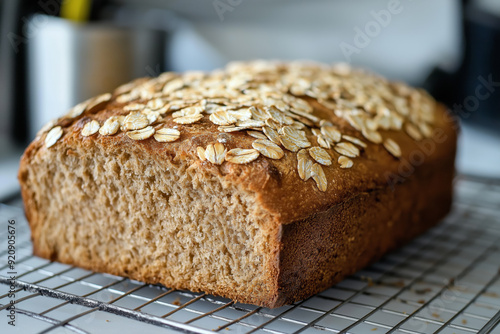 Freshly baked oat bread cooling on a wire rack in a kitchen, showcasing a healthy homemade whole grain loaf topped with oats, perfect for nutritious breakfasts and wholesome living