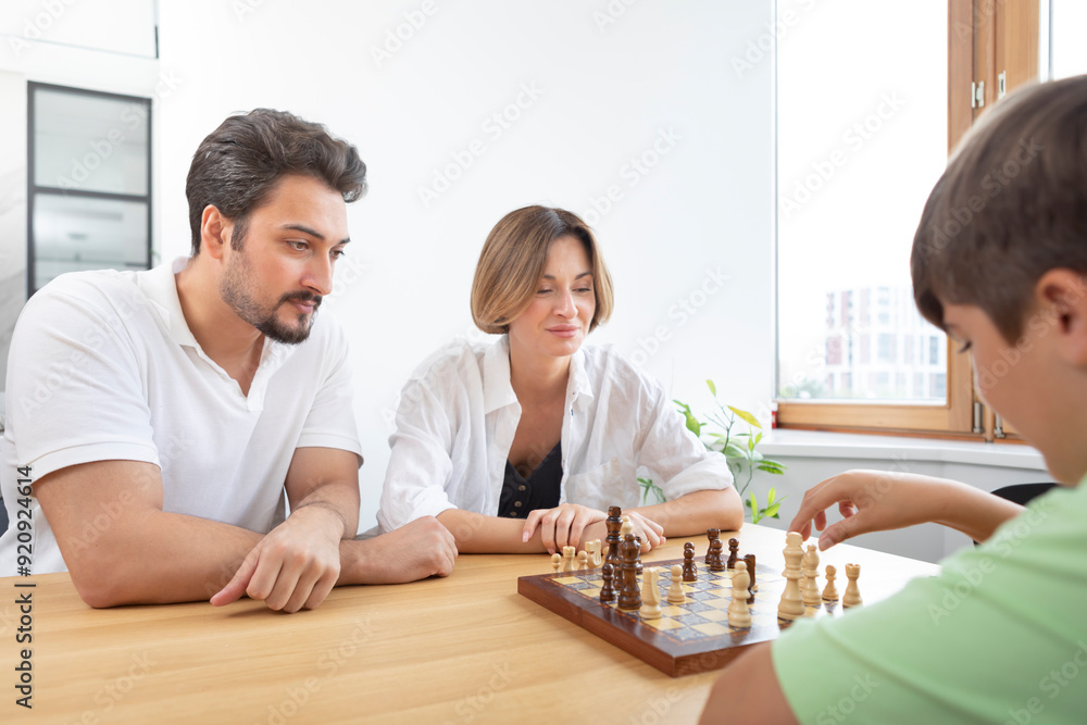 Clever boy plays chess with his parents Clever boy plays chess with his parents