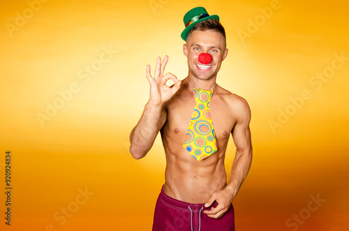 Handsome man in a clown costume. Orange background.