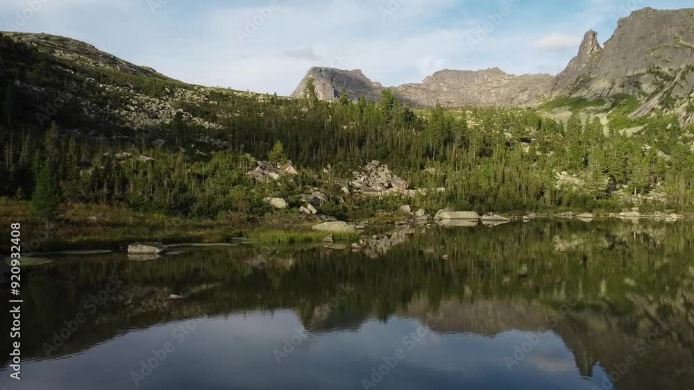 Aerial view of rocky mountains peaks and lake from above. Scenic Lake surrounded by Mountains and trees. Ergaki national park. Beautiful Landscape. Aerial view of rocky mountains peaks and lake from above. Scenic Lake surrounded by Mountains and trees. Ergaki national park. Beautiful Landscape.