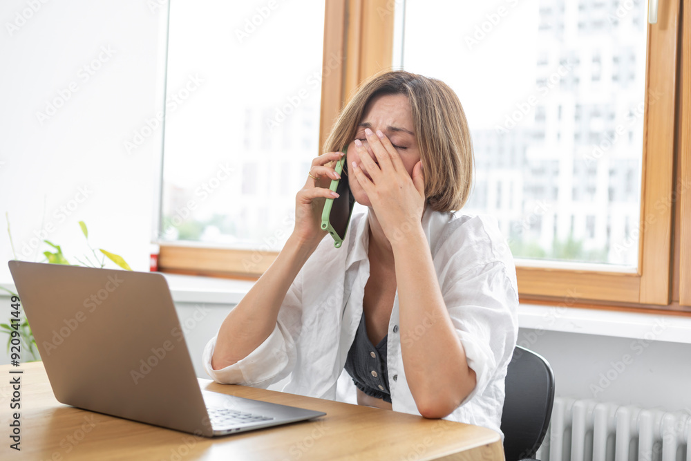 Shocked business woman looking at laptop and talking to mobile phone. She discussing problems in business Shocked business woman looking at laptop and talking to mobile phone. She discussing problems in business