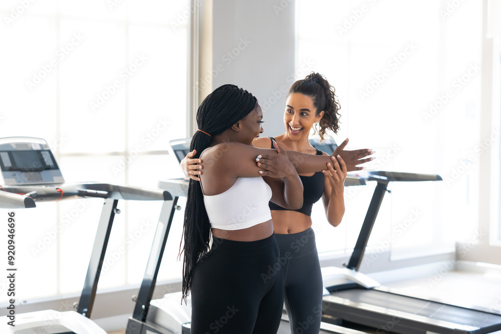 Hispanic female trainer.. beautiful young chubby overweight african american woman wearing sporty fitness clothes doing exercise indoors at gym fitness sport club, body and health care Hispanic female trainer.. beautiful young chubby overweight african american woman wearing sporty fitness clothes doing exercise indoors at gym fitness sport club, body and health care