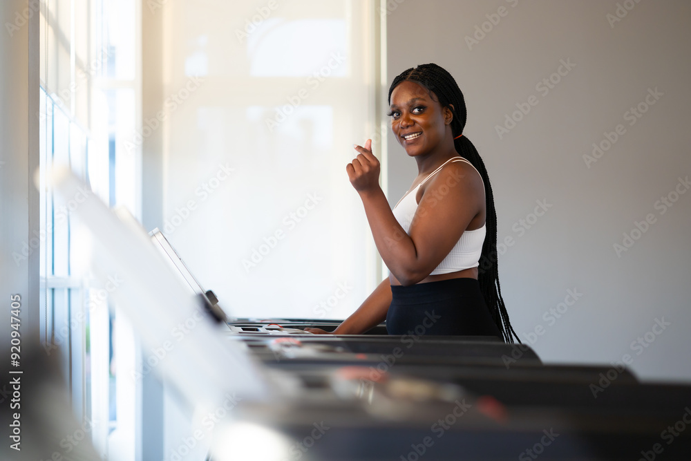 Obraz premium Portrait female jogging on treadmill. beautiful young chubby overweight african american woman wearing sporty fitness clothes doing exercise indoors at gym fitness sport club, body and health care