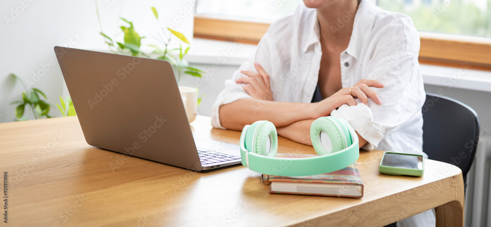 Fototapeta premium Young attractive woman in headphones learning online at home. Distance education concept