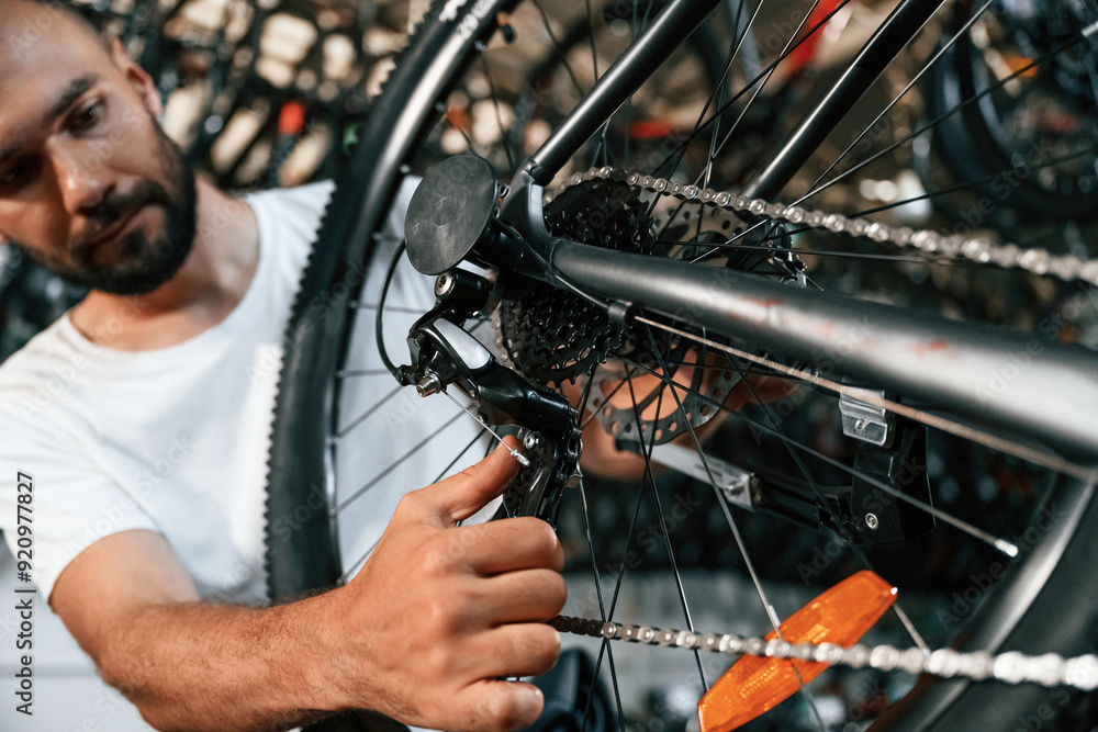 Obraz premium Derailleur adjustment. Repair man in bicycle shop, working in store