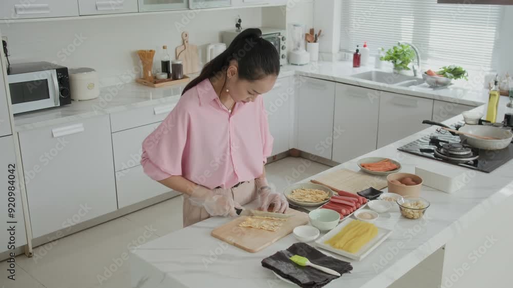 Wide shot of Asian woman cooking gimbap with omelet, sausages and radish while preparing dinner at kitchen Wide shot of Asian woman cooking gimbap with omelet, sausages and radish while preparing dinner at kitchen