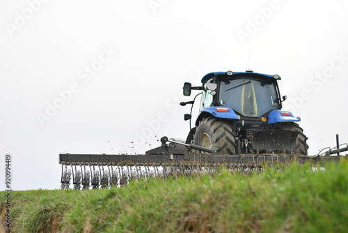 Fotografie Back view of the tractor in the process of harrowing young cereal crops with a r