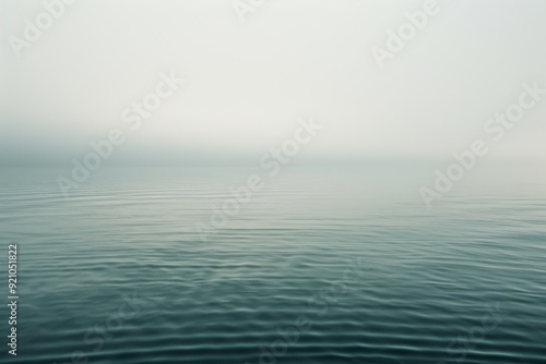 A tranquil lake bordered by rugged mountains, partially obscured by fog, offering a peaceful and ethereal landscape, Subdued tones that evoke a sense of calm, AI generated