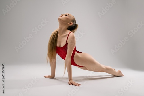 Young Dancer Performing Yoga Pose in Red Attire on Studio Floor