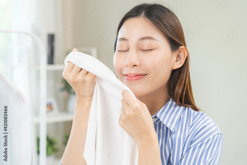 Feel softness, hygiene. Smile asian young woman touching fluffy white shirt smelling fresh clean clothes, pretty girl comfort sniff after washing laundry. Household work at home, chore of maid concept Feel softness, hygiene. Smile asian young woman touching fluffy white shirt smelling fresh clean clothes, pretty girl comfort sniff after washing laundry. Household work at home, chore of maid concept