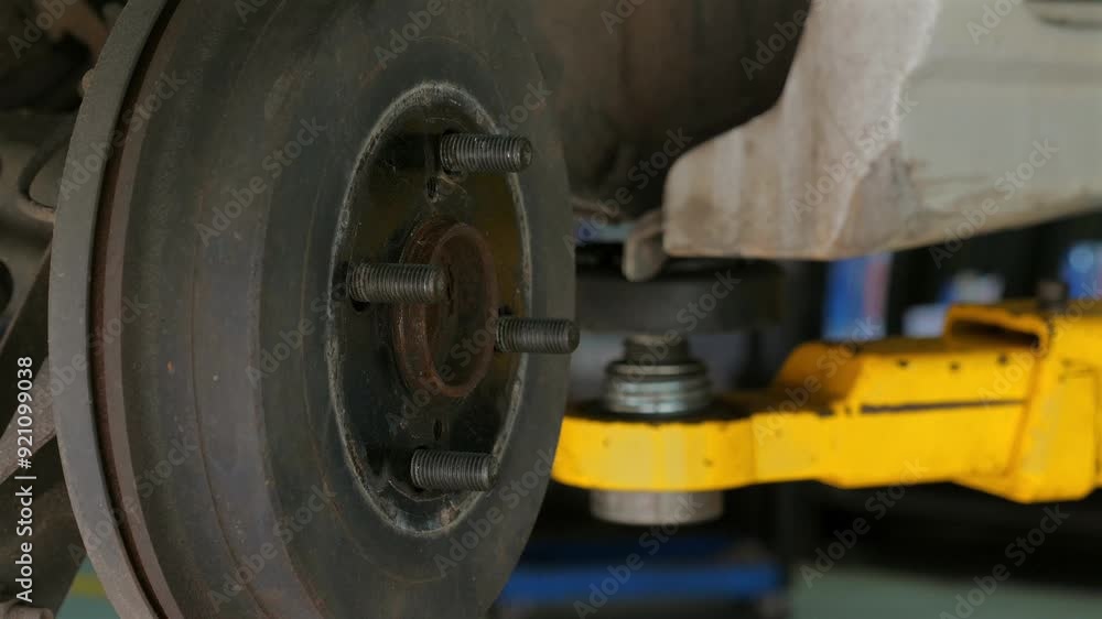 Close-up of car's brake disc and hydraulic lift in auto repair shop, illustrating maintenance and repair services in automotive industry. Auto Repair and Maintenance. Close-up of car's brake disc and hydraulic lift in auto repair shop, illustrating maintenance and repair services in automotive industry. Auto Repair and Maintenance.