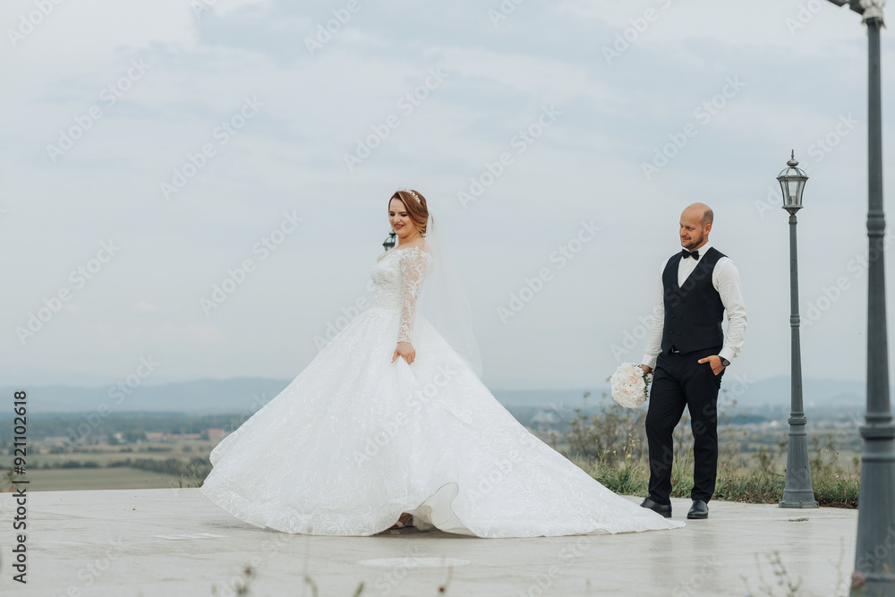 A bride and groom are walking on a path with a beautiful view of the mountains in the background