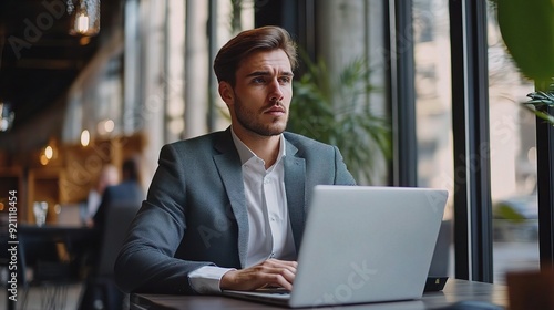 Focused on the Horizon: A young businessman, in a stylish suit, sits thoughtfully in a modern cafe, his eyes fixed on the window view. 