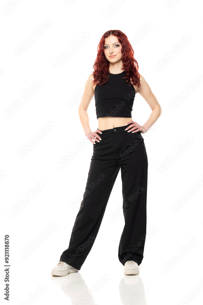 Charming young redhead woman posing in studio in black short blouse and black trousers on a white background Charming young redhead woman posing in studio in black short blouse and black trousers on a white background