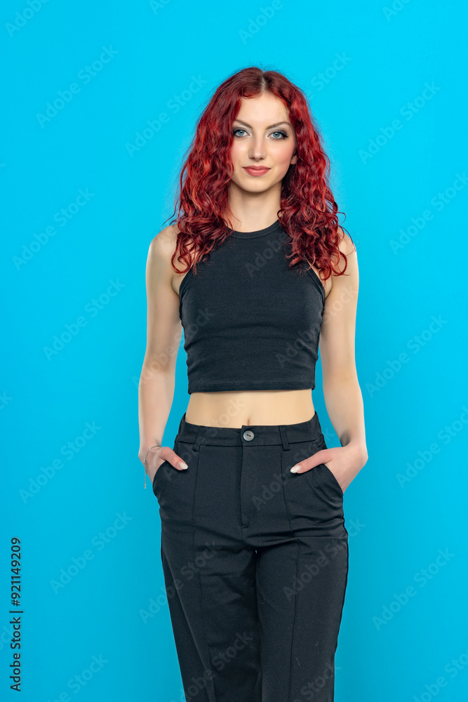 Charming young redhead woman posing in black short blouse and black trousers on a blue backgroun Charming young redhead woman posing in black short blouse and black trousers on a blue backgroun