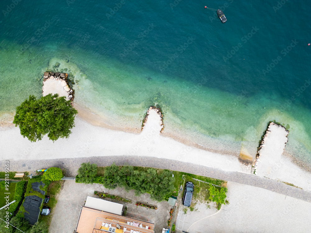 Fototapeta premium Aerial drone view of Lago di Garda (lake Garda) coastline, Italy. The beach and fresh blue water.