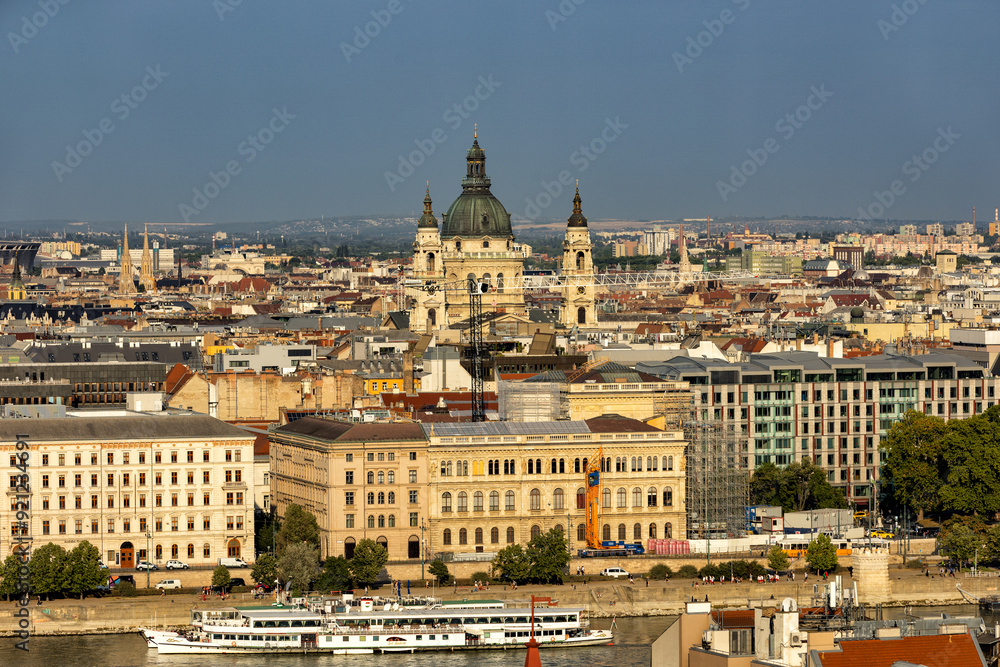 Obraz premium Budapest Hungary. View of the capital in Europe. Cruises ship passes on the Danube River. The imposing Parliament in the background. The bridges with cars, trams and bicycles. Concept photo