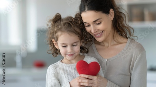 Mother and Daughter Smiling Together Holding a Red Heart in Bright Kitchen