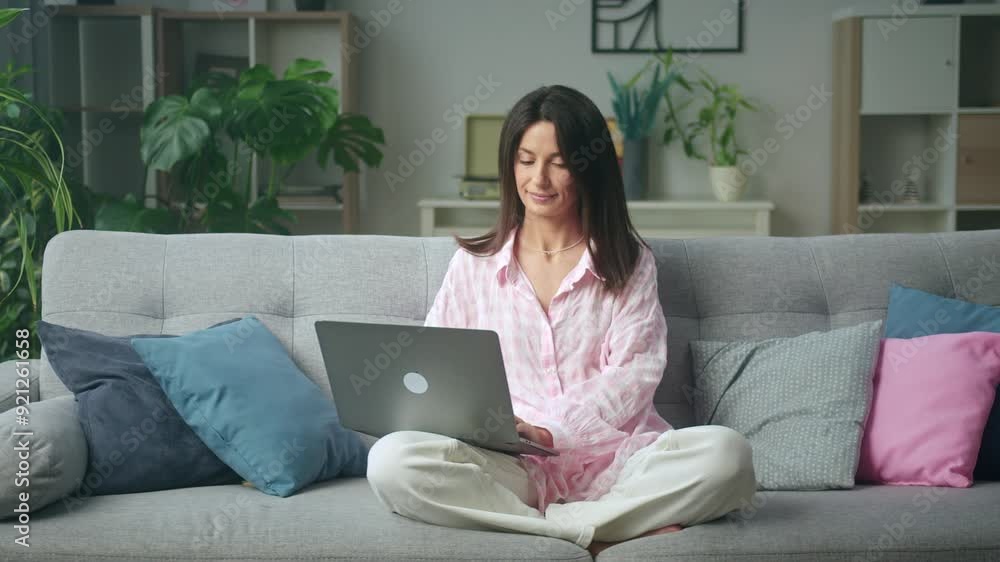 Cozy home office: woman in pajamas working comfortably on laptop Cozy home office: woman in pajamas working comfortably on laptop