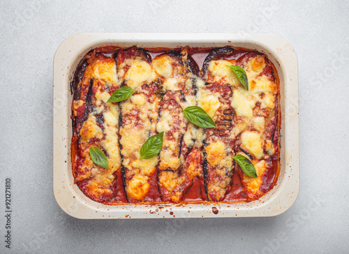 Eggplant parmigiana di melanzane freshly baked and decorated with basil leaves, resting in a baking pan. Classic italian dish