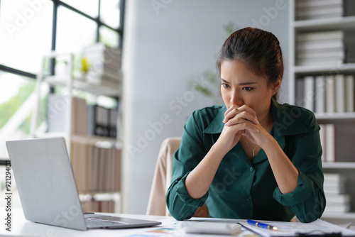 Bild auf Leinwand Young businesswoman is holding her hands together in front of her mouth, looking