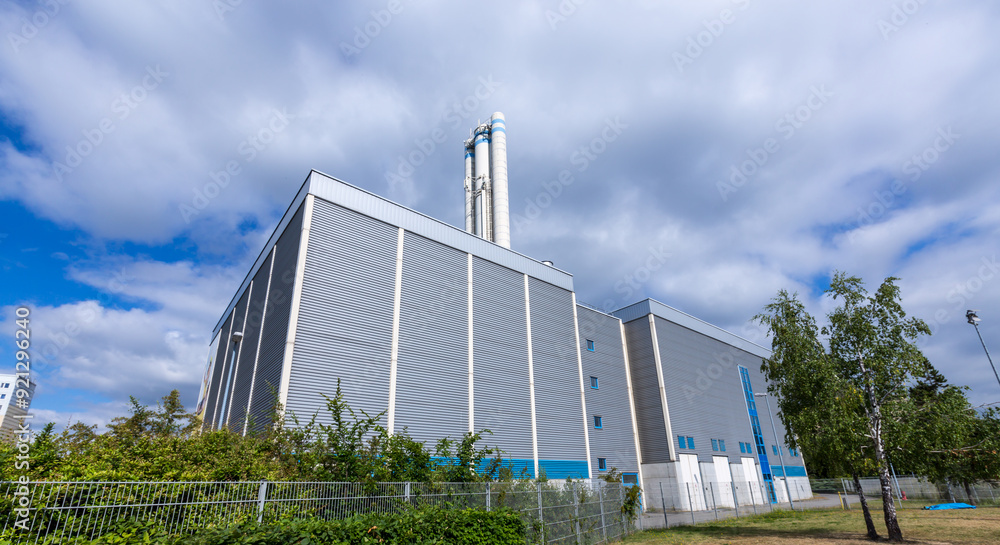 A large industrial building with a tall chimney A large industrial building with a tall chimney