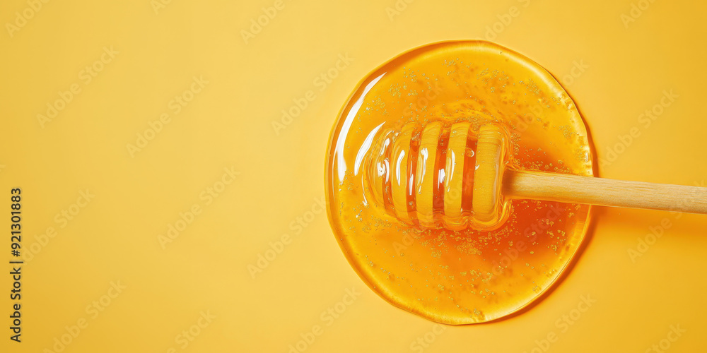 Honey is dripping from a wooden honey dipper onto a yellow background Honey is dripping from a wooden honey dipper onto a yellow background