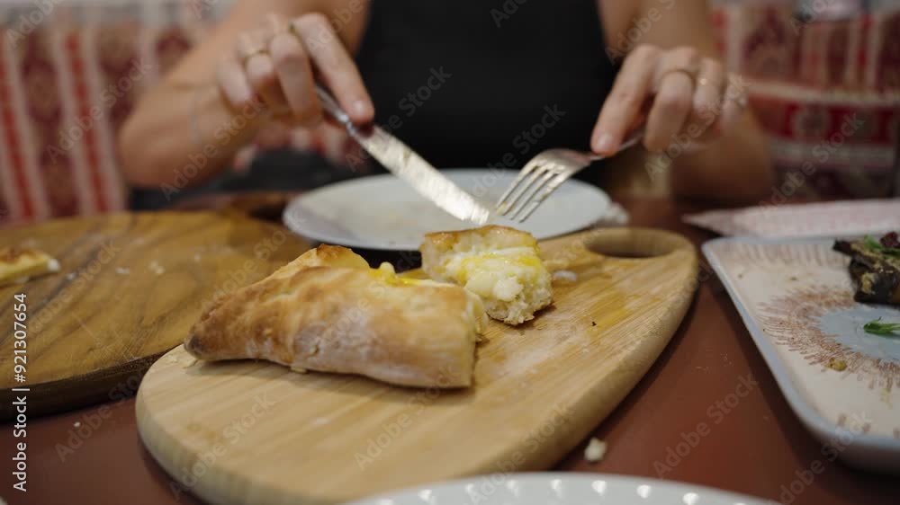 Close-Up of Khachapuri, a young woman slices through the cheesy center. The rich, traditional flavors make it a delicious choice.