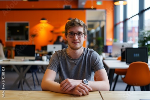 A young man is seated at a desk in an office, engaged in work activities, Internship and work experience