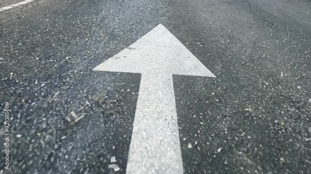 White arrow painted on a asphalt road surface pointing forward, symbolizing direction and progress. Concepts of guidance, navigation, and forward thinking. White arrow painted on a asphalt road surface pointing forward, symbolizing direction and progress. Concepts of guidance, navigation, and forward thinking.