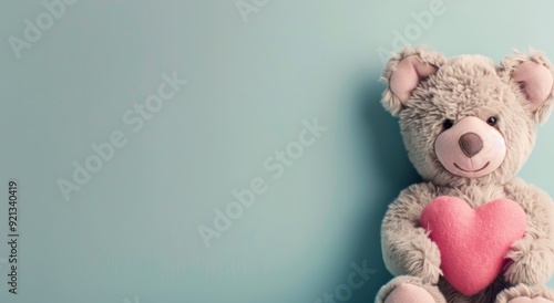 Adorable Teddy Bear Holding Pink Heart Against Soft Blue Background