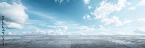 This image features a wide open concrete road stretching into a clear blue sky. The sky is filled with puffy white clouds, symbolizing freedom, possibility, hope, growth, and opportunity. photo