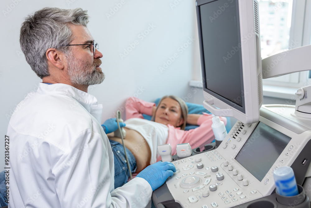 Gray-haired male doctor working with patient and making ultrasonography Gray-haired male doctor working with patient and making ultrasonography