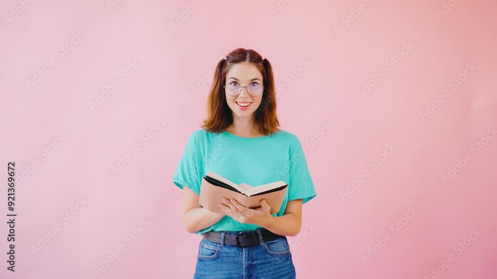 A young woman relaxes against a soft pink wall, absorbed in a captivating book, blending leisure and education in a vibrant atmosphere perfect for creativity and learning A young woman relaxes against a soft pink wall, absorbed in a captivating book, blending leisure and education in a vibrant atmosphere perfect for creativity and learning