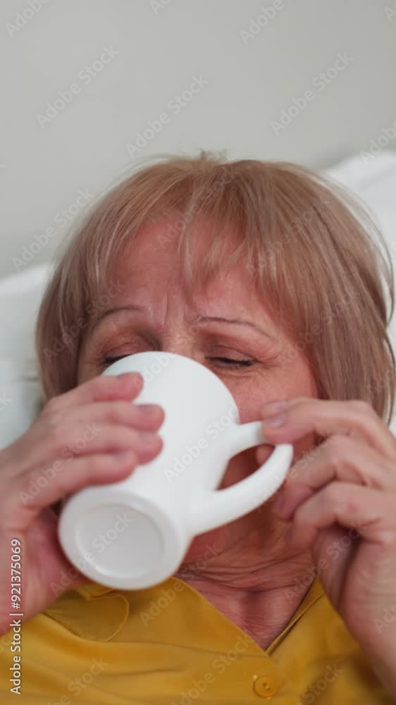 Unquiet old woman drinks pills looking at nurse. Senior person lies on bed resting in sanatorium. Improving health of elderly people closeup Unquiet old woman drinks pills looking at nurse. Senior person lies on bed resting in sanatorium. Improving health of elderly people closeup
