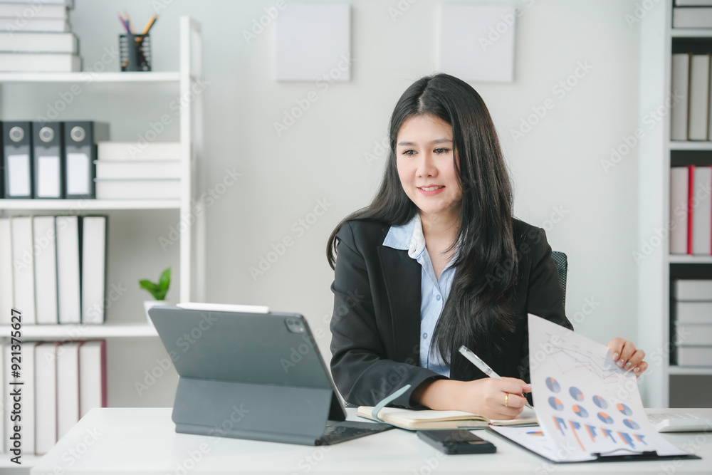 Asian businesswoman working at office using digital tablet and analyzing financial chart documents Asian businesswoman working at office using digital tablet and analyzing financial chart documents