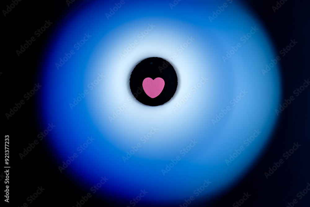 Pink heart surrounded by soft blue glow on black background. Pink heart surrounded by soft blue glow on black background.
