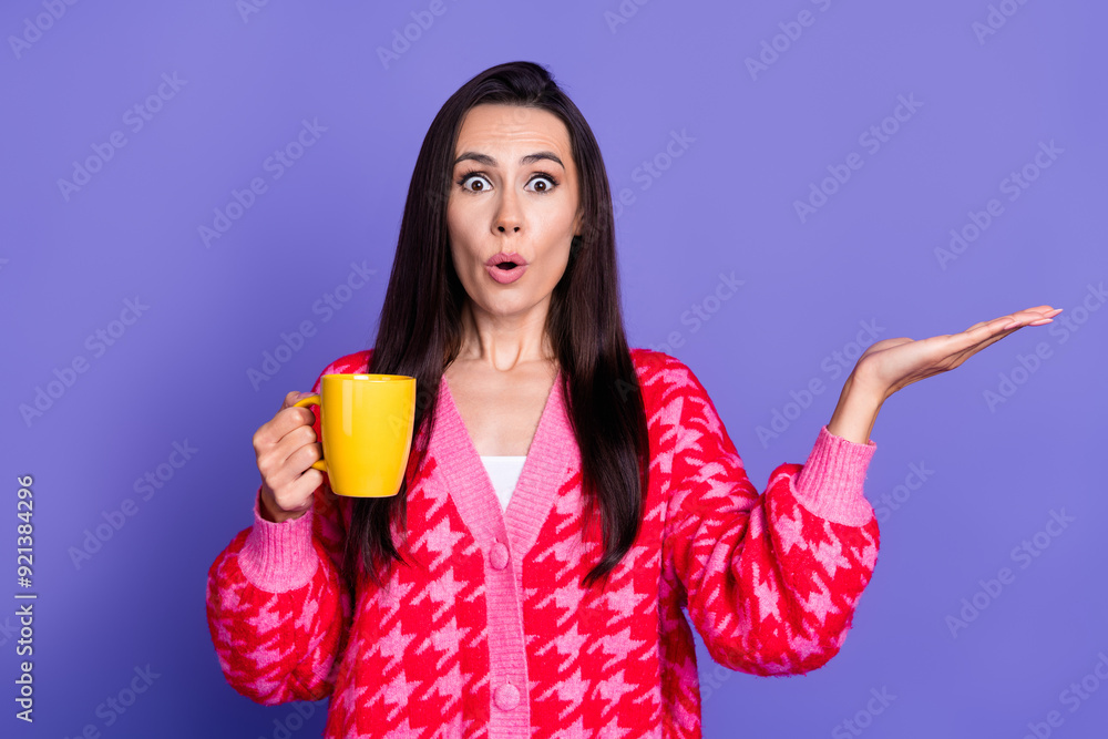Photo of charming impressed woman wear pink cardigan enjoy coffee showing arm empty space isolated purple color background Photo of charming impressed woman wear pink cardigan enjoy coffee showing arm empty space isolated purple color background