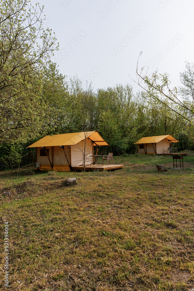 Cozy open glamping tents with light inside in summer camp. Camping tent for holiday and vacation Cozy open glamping tents with light inside in summer camp. Camping tent for holiday and vacation