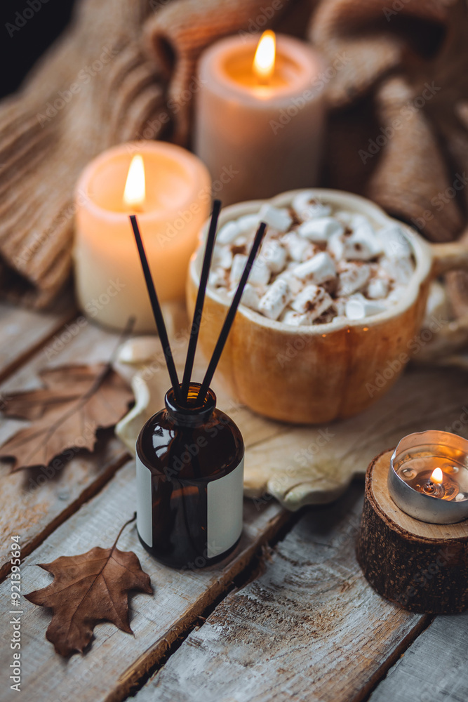Autumn home perfume in glass bottle with wooden sticks, scented candles as apartment air freshener. Pumpkin sweet latte fragrance, spices, cinnamon, anise. Aromatherapy, cozy atmosphere, comfort Autumn home perfume in glass bottle with wooden sticks, scented candles as apartment air freshener. Pumpkin sweet latte fragrance, spices, cinnamon, anise. Aromatherapy, cozy atmosphere, comfort