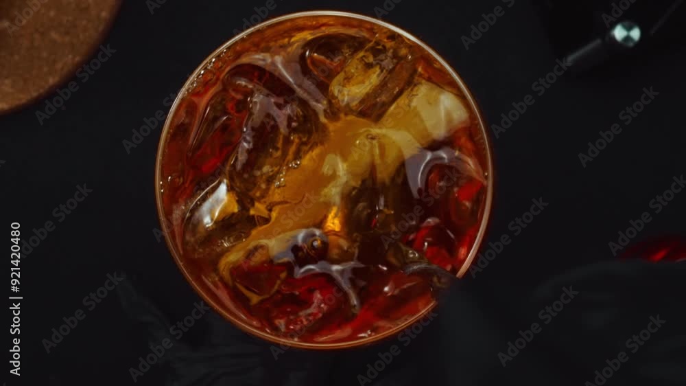 Macrography, experience the art of mixing a Negroni cocktail from a top-down perspective, adorned with a fresh vibrant orange slice, all against a dramatic black background. Alcoholic. Comestible. Macrography, experience the art of mixing a Negroni cocktail from a top-down perspective, adorned with a fresh vibrant orange slice, all against a dramatic black background. Alcoholic. Comestible.