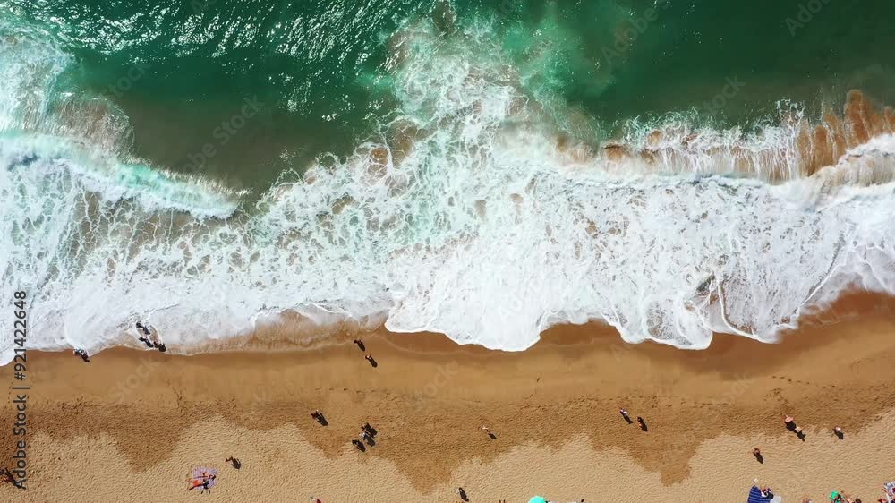 Overhead drone view of sea waves splashing on wet sandy shore at Magoito Beach. From above of unrecognizable people at famous destination in Sintra, Portugal during summer. Overhead drone view of sea waves splashing on wet sandy shore at Magoito Beach. From above of unrecognizable people at famous destination in Sintra, Portugal during summer.
