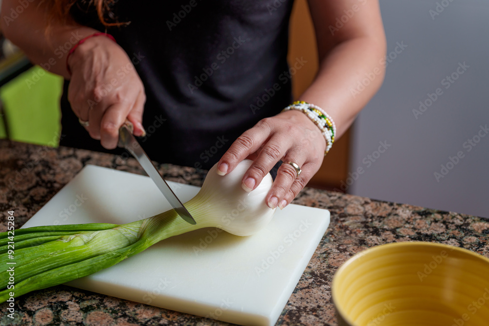 Woman cutting a spring onion on a white board Woman cutting a spring onion on a white board