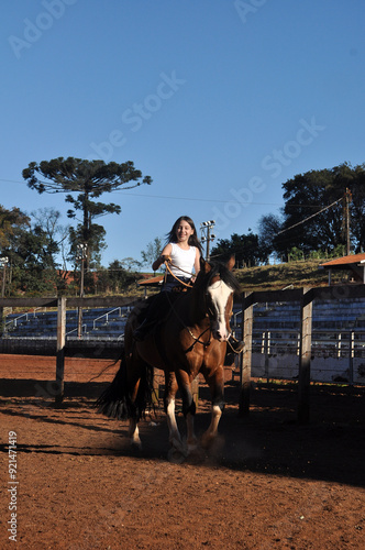 menina vaqueira cavalgando com cavalo marrom  photo