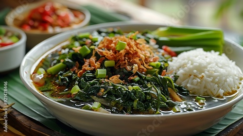 Traditional Indonesian sayur asem kangkung featuring a spicy and sour water spinach soup garnished with fried shallots and served alongside fluffy steamed rice photo