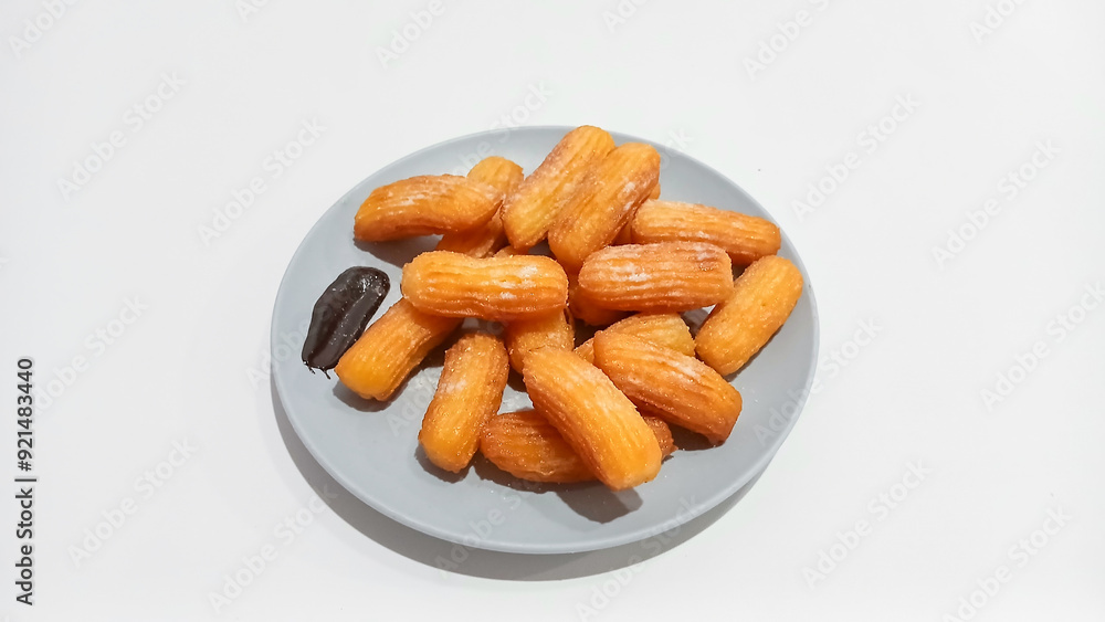 Churros sticks in a small plate with white powdered sugar and a bowl of chocolate sauce Churros sticks in a small plate with white powdered sugar and a bowl of chocolate sauce